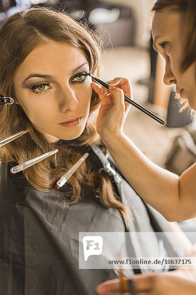 Maskenbildnerin mit Eyeliner auf Mode-Modell