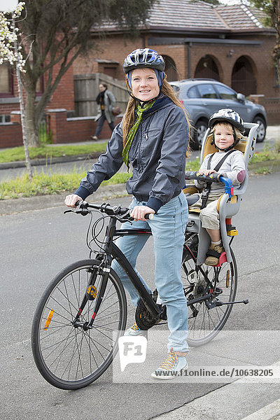 Porträt der Mutter beim Radfahren  während der Sohn auf dem Rücksitz sitzt