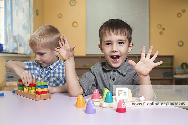 Süße kleine Jungen  die mit Spielzeug am Tisch im Klassenzimmer spielen.