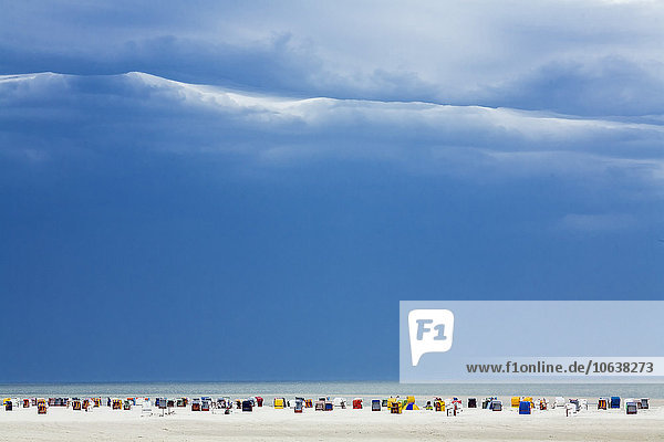 Strandkörbe mit Kapuze am Ufer gegen bewölkten Himmel