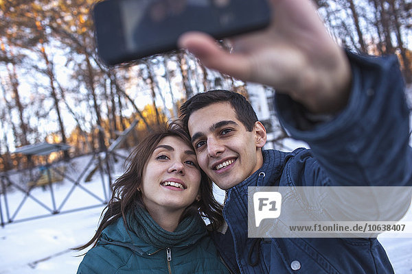 Happy young couple taking selfie through smart phone during winter
