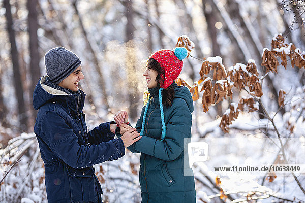 Playful young couple holding hands during winter