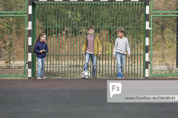 Kinder spielen Fußball auf dem Spielplatz