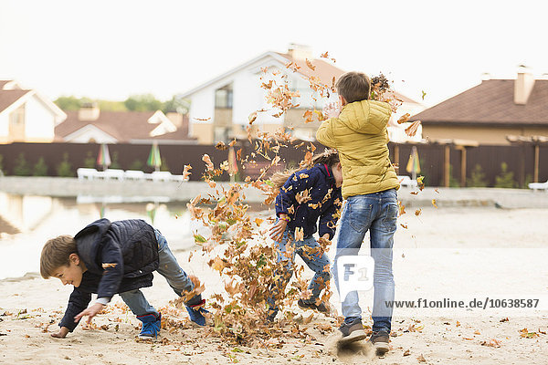 Kinder beim Spielen mit trockenen Blättern auf dem Wanderweg
