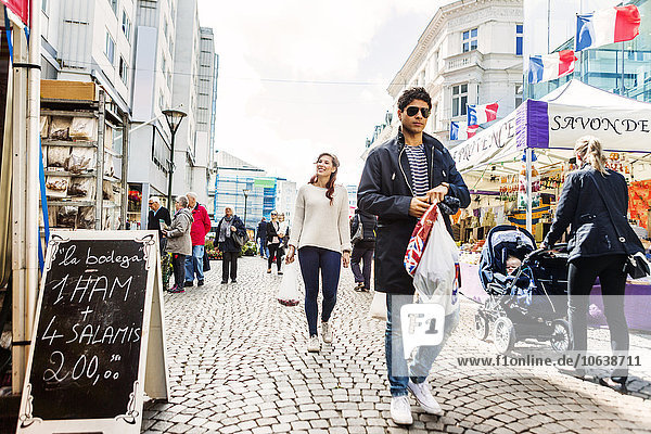 Man carrying shopping bags while walking with friends at market