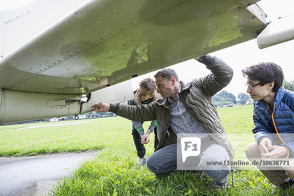 Vater erklärt Söhnen auf dem Feld Flugzeugteile