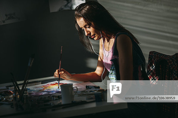 Künstlerin beim Malen am Tisch im Atelier