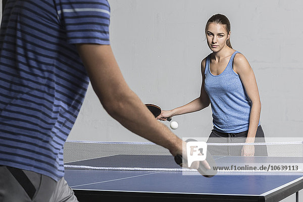 Selbstbewusste junge Frau beim Tischtennisspielen mit Mann