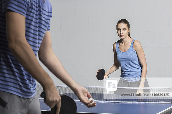 Entschlossene junge Frau beim Tischtennisspielen mit Mann
