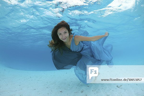 Frau in einem Kleid schwimmt unter Wasser im Meer