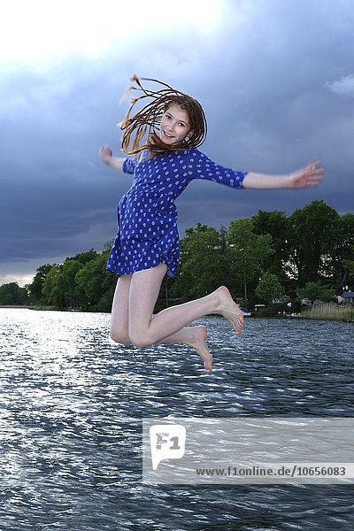 Mädchen springt mit Kleid ins Wasser  dunkle Wolken  Ellbogensee  Obere Havel  bei Priepert  Mecklenburgische Seenplatte  Mecklenburger Seenplatte  Mecklenburg-Vorpommern  Deutschland  Europa