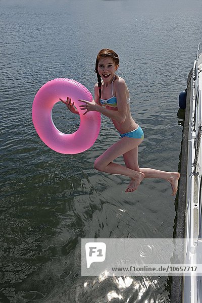 Girl with pink floating tire jumps into the water  Labussee in Canow  Mecklenburg Lake District  Mecklenburg-Western Pomerania  Germany  Europe