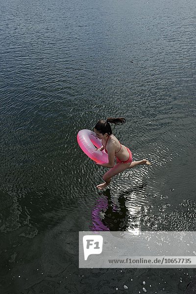 Mädchen mit rosa Schwimmreifen springt ins Wasser  Labussee  bei Canow  Mecklenburgische Seenplatte  Mecklenburg-Vorpommern  Deutschland  Europa