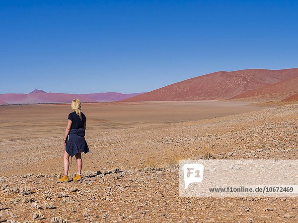 Frau steht an der Namib Wüste und betrachtet die Landschaft  Tsarisberge  Hammerstein  Sossusvlei  Namib-Naukluft-Park  Namibia  Afrika
