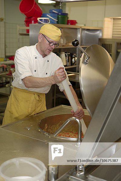 Koch rührt in großem Kochbehälter  Kantinenküche  Grossküche  Deutschland  Europa