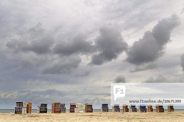 Verlassene Strandkörbe vor dunklen Wolken am Strand von Prerow  Vorpommersche Boddenlandschaft  Mecklenburg-Vorpommern  Deutschland  Europa