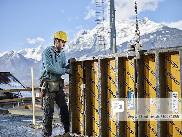 Construction worker lifting shuttering wall with crane  preparing framed formwork  Kolsass  Innsbruck Land  Tyrol  Austria  Europe