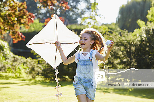 Enthusiastic girl running with kite in sunny garden