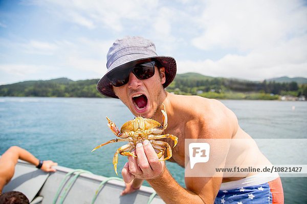 Portrait of mid adult man holding crab on fishing boat  Nehalem Bay  Oregon  USA