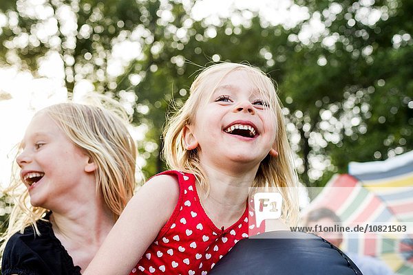 Zwei junge Schwestern beim Spielen auf Hüpfburgen im Park