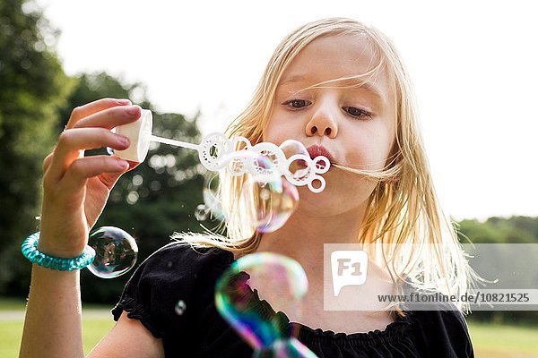 Porträt eines süßen Mädchens  das Blasen im Park bläst.