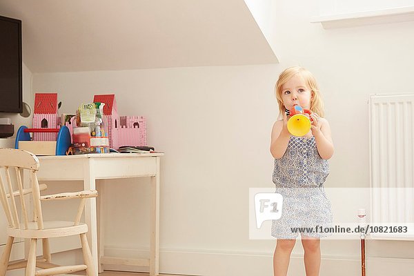 Porträt eines Kleinkindes im Spielzimmer mit Spielzeugtrompete