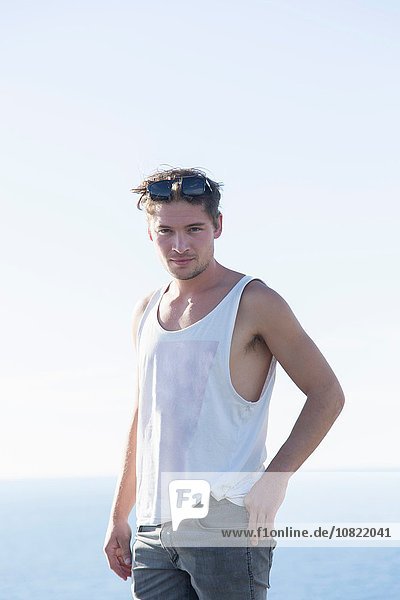 Young man in vest wearing sunglasses on head looking at camera smiling  Capo Caccia  Sardinia  Italy