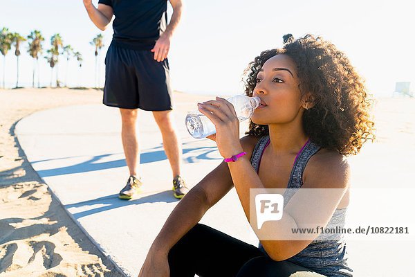 Mid adult woman  by beach  drinking from water bottle