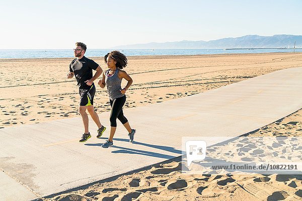 Couple running on pathway at beach