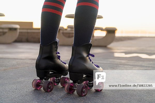 Mid adult woman on rollerskates  rear view  low section