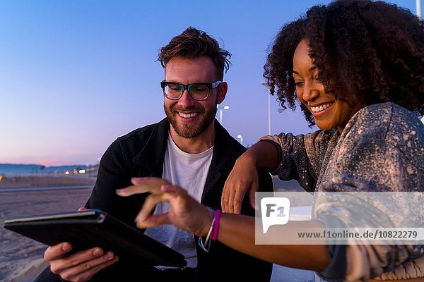 Paar im Freien  neben dem Strand  mit Blick auf das digitale Tablett