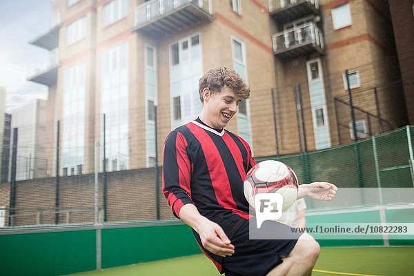 Junger Mann trainiert Fußball auf dem städtischen Fußballplatz