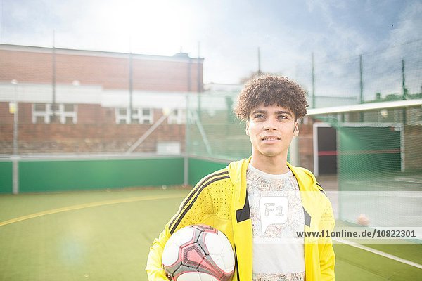 Porträt eines jungen Mannes  der Fußball hält  auf dem Stadtfußballplatz