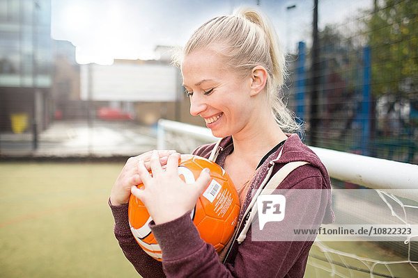 Junge Frau hält Fußball  lächelnd