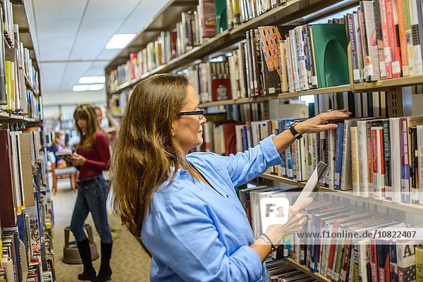 Reife Frau bei der Auswahl von Büchern in der Bibliothek