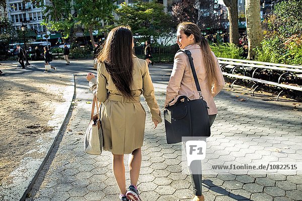 Rückansicht junger weiblicher Zwillinge beim Spaziergang durch den Stadtpark