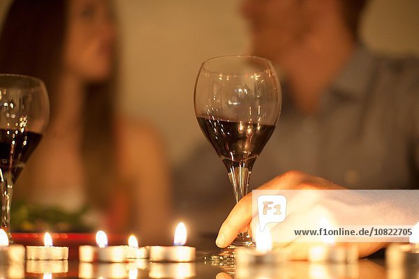 Couple enjoying a glass of red wine by candlelight