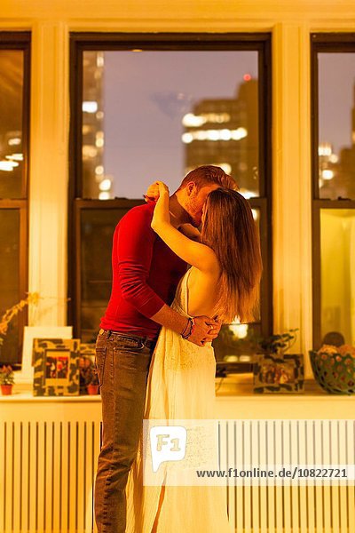 Seitenansicht des Paares in der Wohnung stehend küssend
