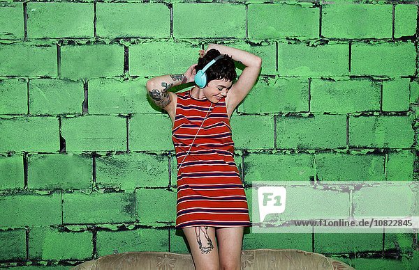 Mittlere erwachsene Frau mit Tattoos  Kopfhörer tragend  tanzend