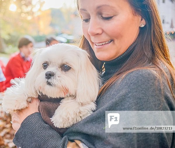 Close up portrait of mature woman carrying dog in arms