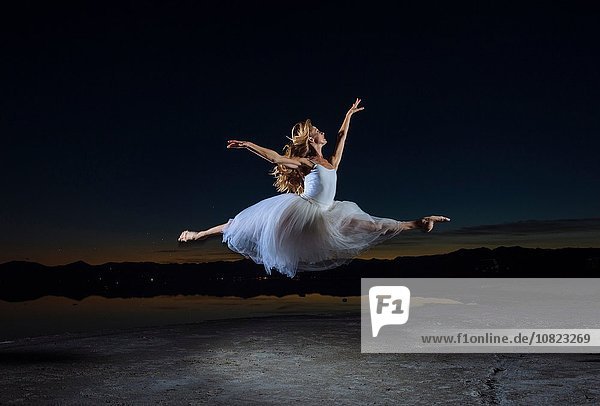 Junge Balletttänzerin beim Sprung über Bonneville Salt Flats bei Nacht  Utah  USA