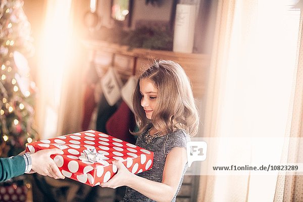 Side view of girl receiving gift at christmas looking down smiling