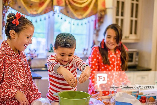 Kinder in der Küche mit Pyjamas  die Eier in die Rührschüssel knallen  lächelnd
