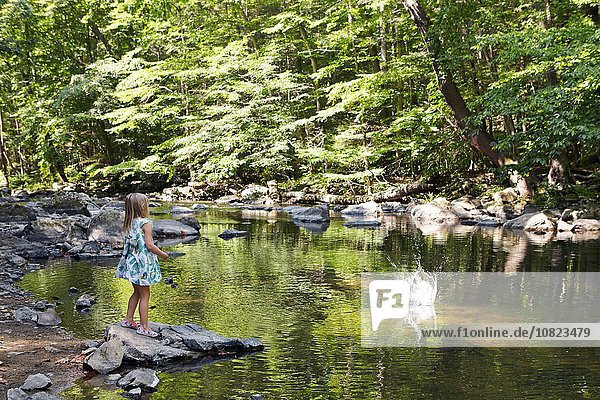 Mädchen wirft Stein in den Fluss