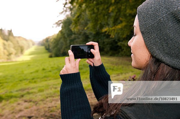 Young woman photographing field on smartphone