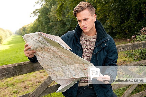 Junger Mann  der sich gegen die Landkarte lehnt.