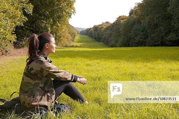 Junge Frau auf dem Feld sitzend mit Blick auf die Landschaft  Great Missenden  Buckinghamshire  U.K.