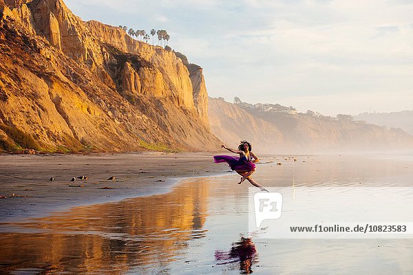 Junge Tänzerin  springend  in der Luft  über Wasser am Strand  San Diego  Kalifornien  USA