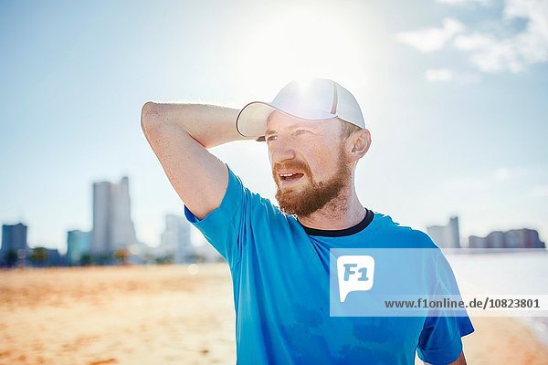 Mittlerer erwachsener Mann mit Baseballmütze,  Hand hinter dem Kopf wegblickend,  Dubai,  Vereinigte Arabische Emirate
