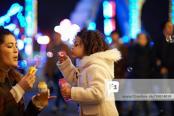 Mother and daughter blowing bubbles  at funfair